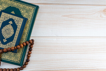 Poster - Holy Quran with arabic calligraphies translation meaning of Al-Quran and Rosary or Tasbih on wooden background. Ramadan,Hajj, Islamic and Copy Space concept