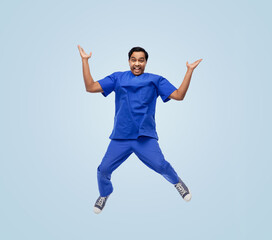 Wall Mural - healthcare, profession and medicine concept - happy smiling indian doctor or male nurse in uniform jumping in air over blue background