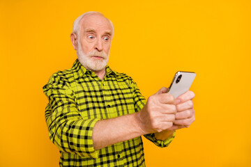 Poster - Photo of amazed old man hold telephone look screen crazy face wear plaid green shirt isolated yellow color background