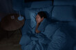 people, relax and comfort concept - young african american woman sleeping in bed at home at night