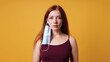 © Axel Bueckert - young woman with medical face mask hanging from her ear - improper use of protective corona coronavirus covid mask