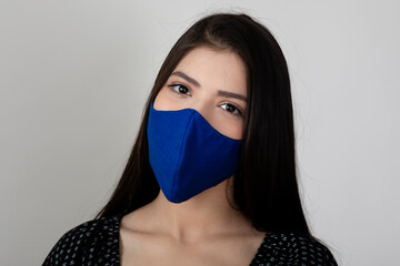 Image of a pretty young girl wearing Covid 19 protection mask and standing against white background.