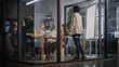 © Gorodenkoff - Project Manager Makes a Presentation for a Young Diverse Creative Team in Meeting Room in an Agency. Colleagues Sit Behind Conference Table and Discuss Business Development, User Interface and Design.