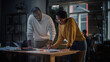 © Gorodenkoff - Two Diverse Multiethnic Colleagues Have a Conversation in a Meeting Room Behind Glass Walls in an Agency. African American Creative Director and Female Project Manager Discuss Work on Laptop Computer.
