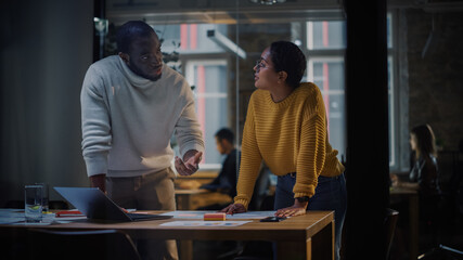 Aufkleber - Two Diverse Multiethnic Colleagues Have a Conversation in a Meeting Room Behind Glass Walls in an Agency. African American Creative Director and Female Project Manager Discuss Work on Laptop Computer.