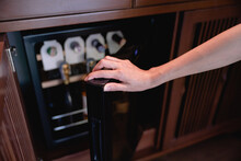 Woman Hand Open Storing Bottles Of Wine In Fridge. Cooling And Preserving Wine.