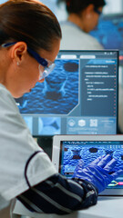 Scientist using digital tablet working in modern medical research laboratory, analyzing DNA information. Medicine, biotechnology research in advanced pharma lab, examining virus evolution