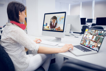 Poster - Female teacher wearing headphones having a video call with multiple students at school on laptop and