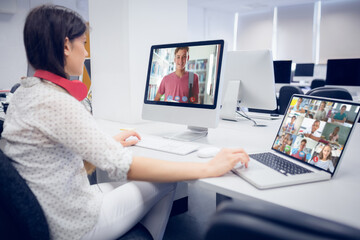 Poster - Female teacher wearing headphones having a video call with multiple students at school on laptop and