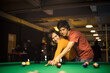 © liderina - Young couple spending time in billiard room. Boyfriend teaching his girlfriend to playing billiard.