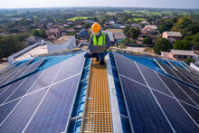 Asian Technician Checks The Maintenance Of The Solar Panels On The Roof.