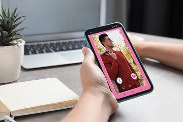 Poster - Woman visiting dating site via smartphone at table, closeup