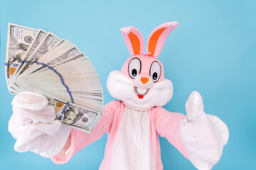 Wall Mural - Rich lucky happy man or boy or kid millionaire or billionaire holds fan of dollars, shows thumb finger up, having fun. Easter bunny or rabbit or hare with dollar, celebrate Happy easter