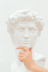 Women's hand holds a chin of the plastic sculpture of a man.Emotions, thoughtfulness,
creative concept.