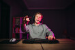 © bodnarphoto - Happy young male gamer in headset and casual makes streaming game and communicates with subscribers and shows finger to camera and smiles.