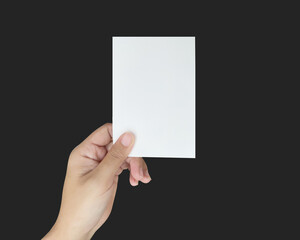 a close up of two hands holding a blank white paper. showing a virtual business card template on the black background.