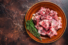 Raw Mutton Meat Diced For Goulash Or Stew With Bone On A Rustic Plate. Dark Background. Top View. Copy Space
