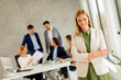© BGStock72 - Young business woman standing in the office in front of her team
