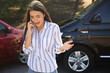 © New Africa - Stressed woman talking on phone after car accident outdoors