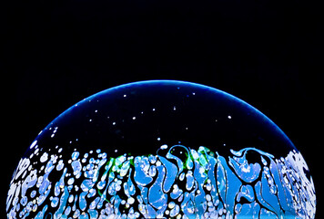 Poster - Closeup shot of a bubble with blue abstract patterns on a dark background