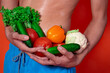 © Denis - A beautiful male body and natural vegetables. Diet and nutrition. Orange background. Broccoli, tomatoes, cucumbers, peppers and lettuce.
