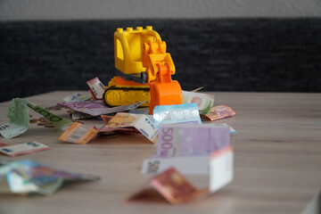 Sticker - Selective focus shot of different euro banknotes with a yellow plastic excavator toy