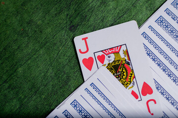 Closeup view of some Poker playing Cards over a green Texture wooden table
