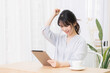 © garage38 - 部屋でタブレットを使いながらガッポーズをする若い女性