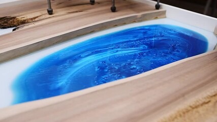 Wall Mural - Process making of a craft resin and wood table. Liquid epoxy is poured into a mold with wooden blanks.