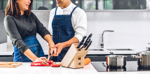 Wall Mural - Young asian family couple having fun cooking together with fresh vegetable salad on table.Happy couple prepare the yummy eating lunch in kitchen