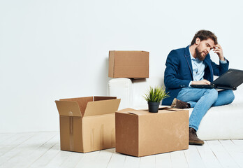 Business man sitting on the couch with laptop boxes with things unpacking office official