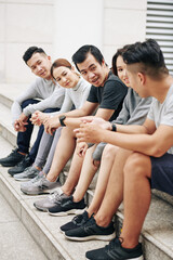 Canvas Print - Group of fit friends sitting on steps and discussing half marathon they are preparing for