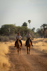 Poster - Two horsewomen ride side-by-side along dirt track