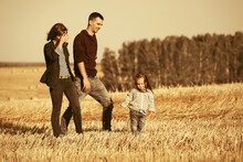 Happy Young Family With Two Year Old Girl Walking In Harvested Field