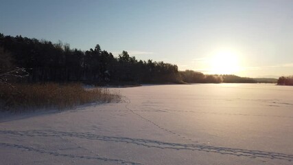 Wall Mural - The sun has just risen and lights up a frozen lake in Scandinavia