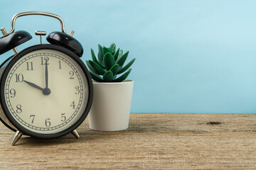 Black vintage alarm clock on a shabby wooden board background shows the time ten hours. Copy space.