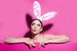 Easter young woman studio wearing bunny ears. curious isolated on pink.