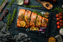 Salmon. Pieces Of Grilled Fish On A Black Stone Background. Recipe. Seafood. Free Space For Text.