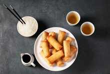 Stand With Tasty Fried Spring Rolls And Sauce On Dark Background