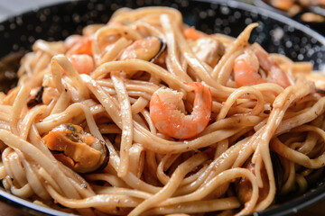 Frying pan with tasty noodles and seafood, closeup