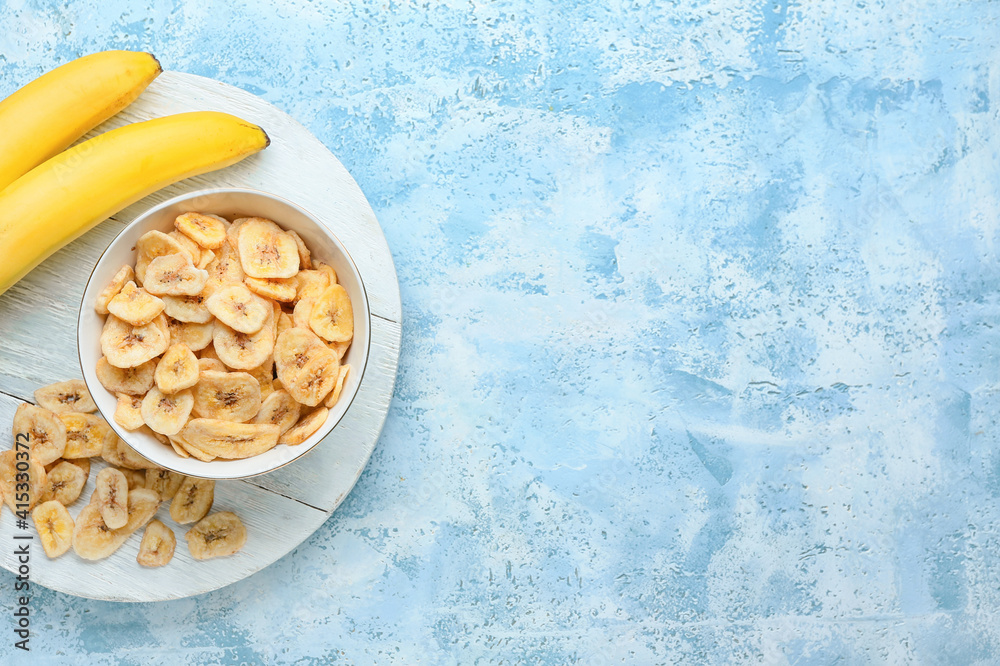 Fresh bananas and crispy chips on color background
