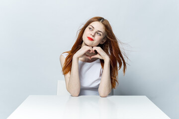 cheerful woman sitting at the table red lips charm gesture hands studio