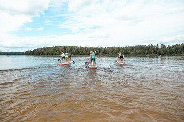 Wall Mural - Stand up paddle SUP race competition. People rowing with Dragon boards in SUP festival.