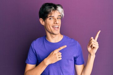 Young hispanic man wearing casual clothes smiling and looking at the camera pointing with two hands and fingers to the side.