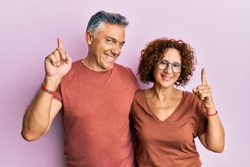 Poster - Beautiful middle age couple together wearing casual clothes pointing finger up with successful idea. exited and happy. number one.