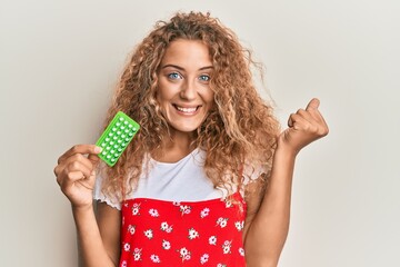 Poster - Beautiful caucasian teenager girl holding birth control pills screaming proud, celebrating victory and success very excited with raised arm