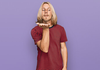 Sticker - Caucasian man with blond long hair wearing casual striped t shirt looking at the camera blowing a kiss with hand on air being lovely and sexy. love expression.