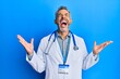© Krakenimages.com - Middle age grey-haired man wearing doctor uniform and stethoscope celebrating mad and crazy for success with arms raised and closed eyes screaming excited. winner concept