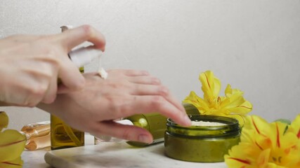 Poster - Female hands care, spa concept. Natural body scrub and flowers on marble background. Cosmetic moistening cream container with skincare product.