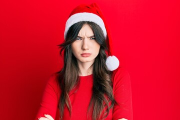 Sticker - Young beautiful caucasian girl wearing christmas hat skeptic and nervous, disapproving expression on face with crossed arms. negative person.